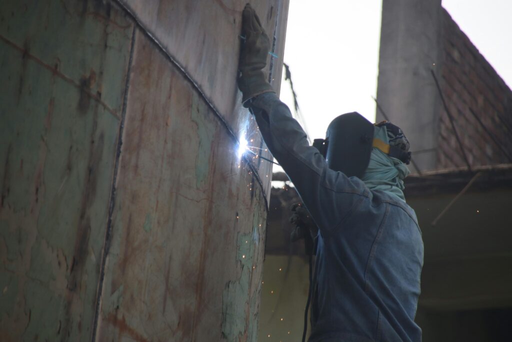 A welder works on a ship hull in Keraniganj shipyard, showcasing skilled labor in industrial settings.