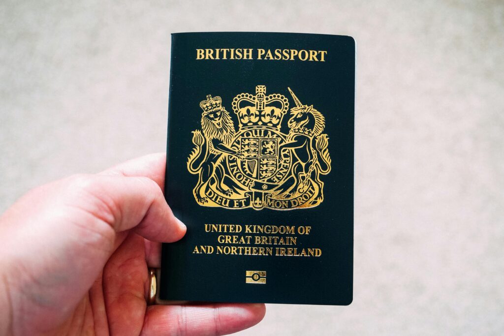 High angle crop anonymous person showing national British passport against blurred gray ground
