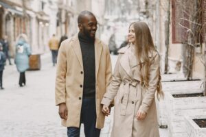 Insights A joyful multiracial couple holding hands and walking in a winter urban setting.